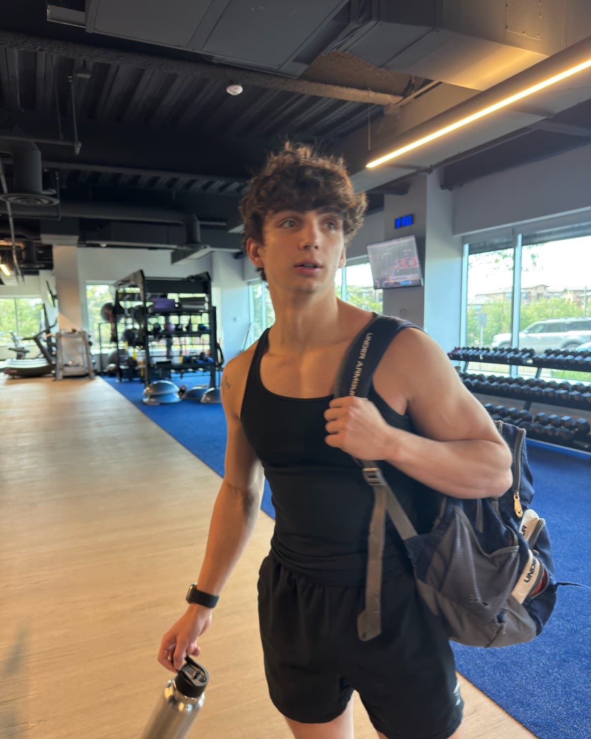 Kris Oddo walking through the gym with his bag and shaker