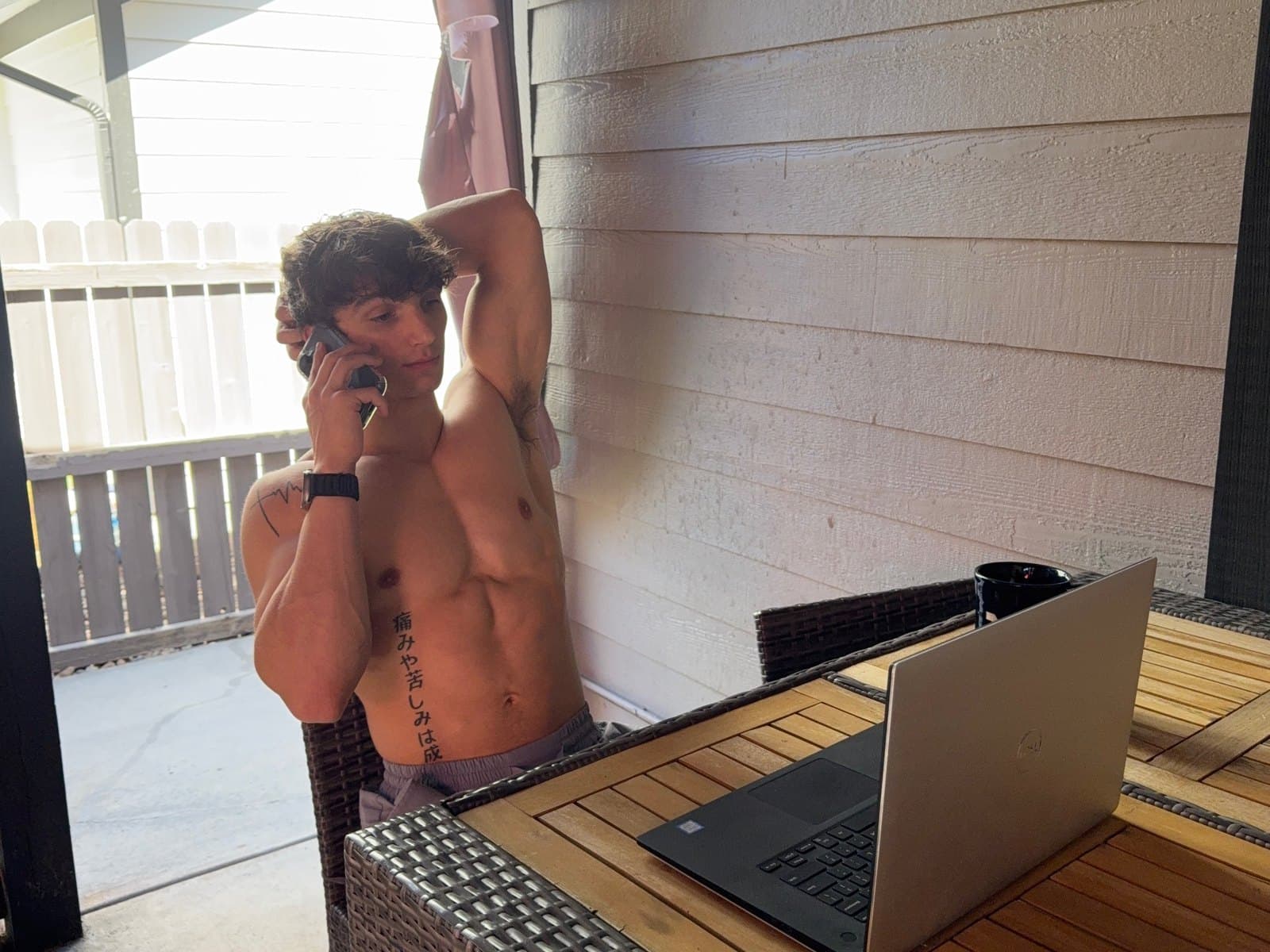Kris Oddo on his porch taking a call, laptop open on the table beside him